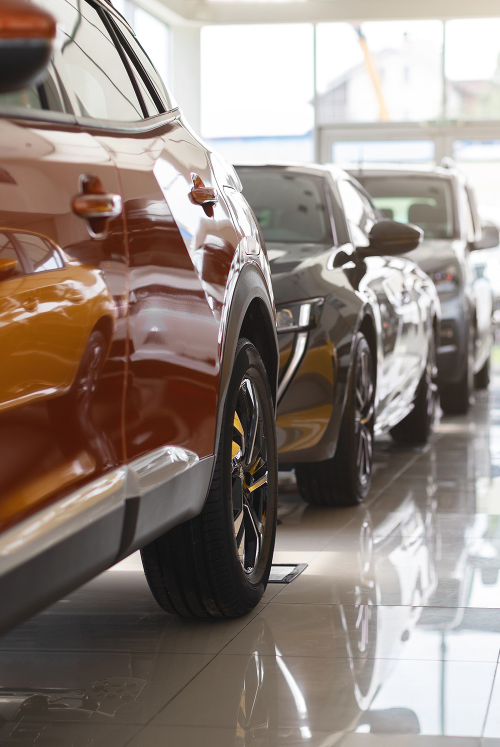 A lineup of cars in a showroom, symbolising Readywire’s comprehensive solution tailored for auto dealership management and operations.